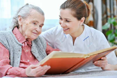 Senior women and nurse looking together at album with old photographs